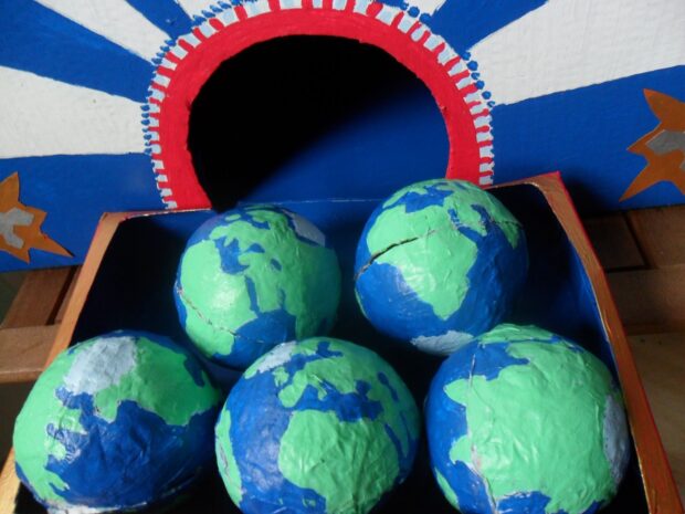 A photo of 5 paper mache models of the Earth.Created by Deborah Mason for the On Some Other World project. 