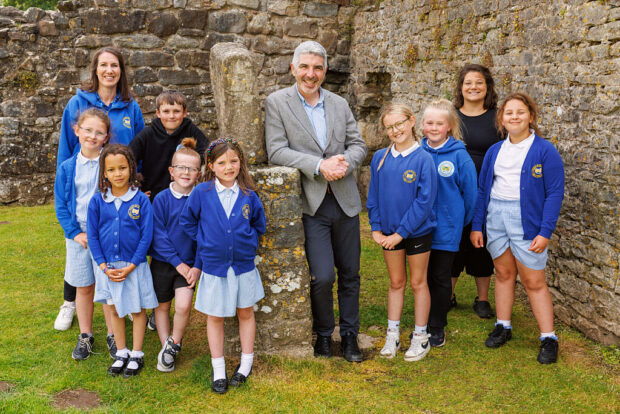 A photo of Derek Walker, the current Future Generations Commissioner for Wales with a group of primary school children and their teachers.